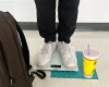 Two feet on a scale. On the ground is a Booster Juice cup.