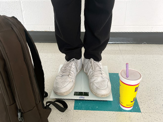 Two feet on a scale. On the ground is a Booster Juice cup.