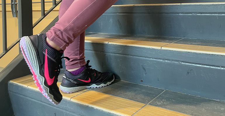 A photo of a person in running shoes walking up a set of stairs.