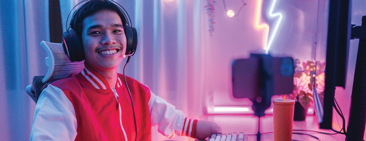 A stock image of a young person at a computer set-up wearing a gaming headset.