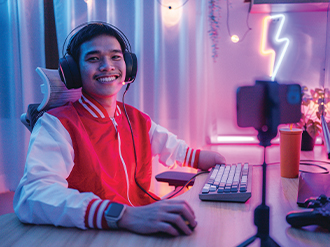 A stock image of a young person at a computer set-up wearing a gaming headset.